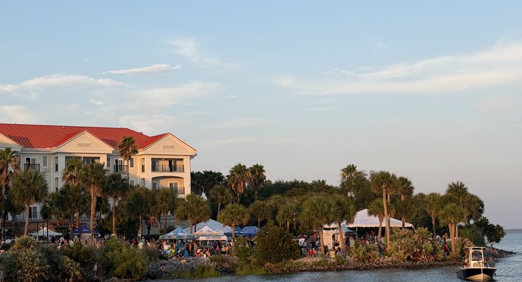 Waterfront view of Party at the Point at Charleston Harbor Resort and Marina with crowds, tents, palm trees, and boats on the harbor, Mount Pleasant SC