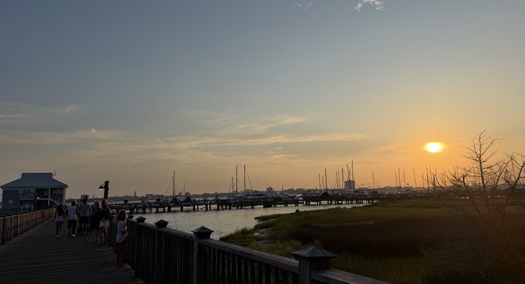 Sunset view from the boardwalk at Charleston Harbor Resort and Marina with families walking and sailboats in the harbor, Mount Pleasant SC