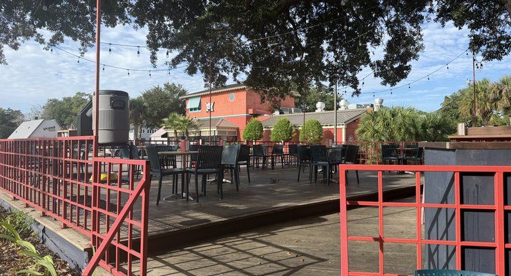 Outdoor patio at Bodega with string lights, tables and chairs under oak trees