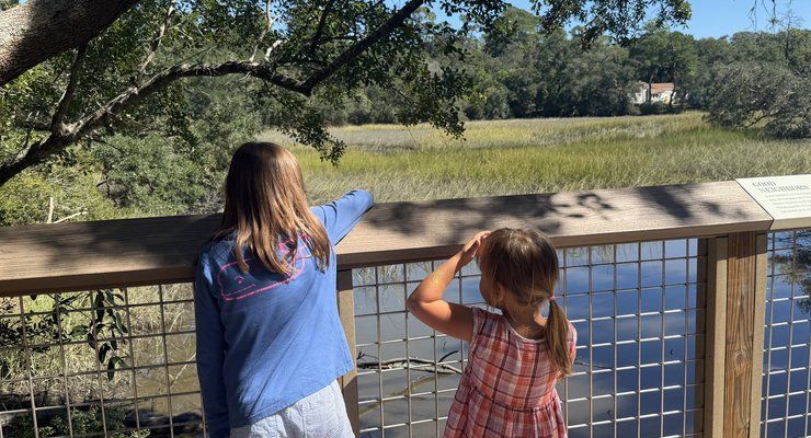 Two girls looking out over the salt marsh from a railing at Old Towne Creek County Park