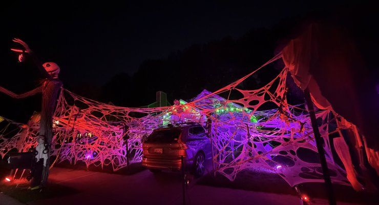 Giant glowing spider web stretched over a driveway and yard at night on Peninsula Cove Drive in Charleston, SC