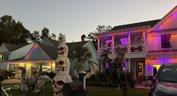 Front yard Halloween display with giant skeletons and a tower of skulls at dusk off Clements Ferry Road in Charleston, SC