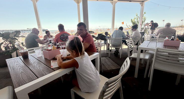 Family eating at an oceanfront patio table at Pinky's on the Beach in Folly Beach