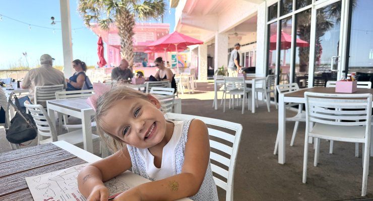 Smiling little girl at an outdoor table on the patio at Pinky's on the Beach