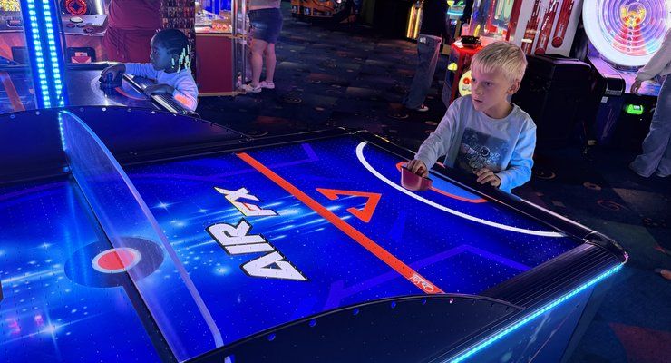 Young boy playing a glowing air hockey table in the arcade at Stars and Strikes in Summerville, SC