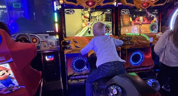Child playing a ride-on motorcycle racing arcade game at Stars and Strikes in Summerville, SC