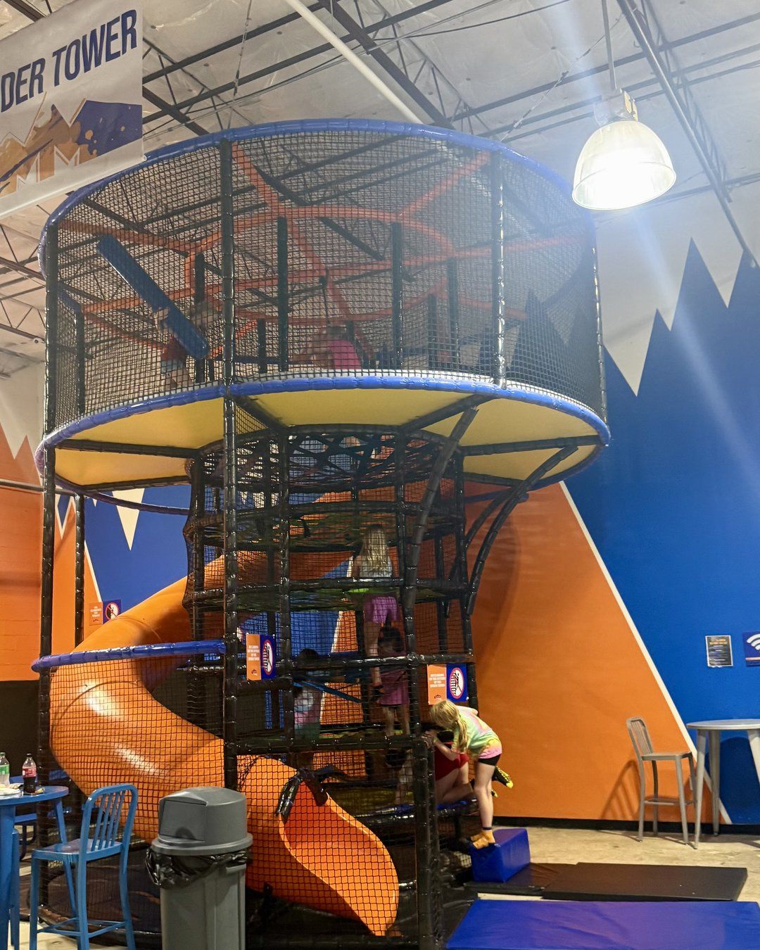 Kids climbing the Spider Tower with an orange spiral slide at Summit Adventure Park in West Ashley